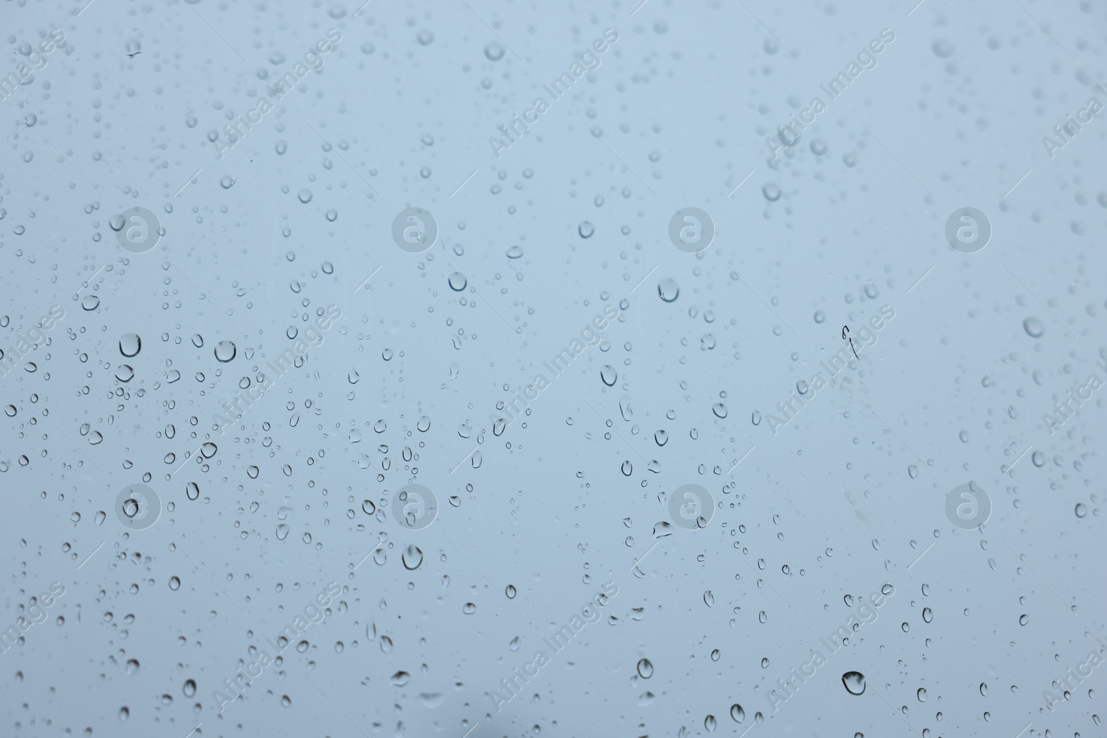 Photo of View on sky through window with water droplets on rainy day, closeup