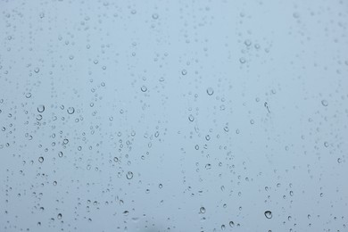 View on sky through window with water droplets on rainy day, closeup