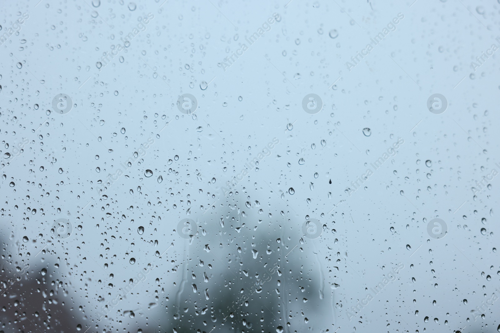 Photo of View on sky through window with water droplets on rainy day, closeup