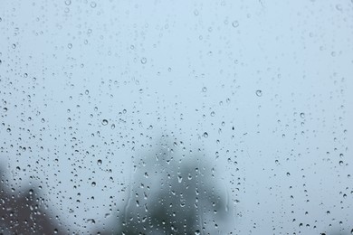 View on sky through window with water droplets on rainy day, closeup