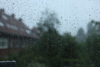 Photo of View on buildings through window with water droplets on rainy day, closeup