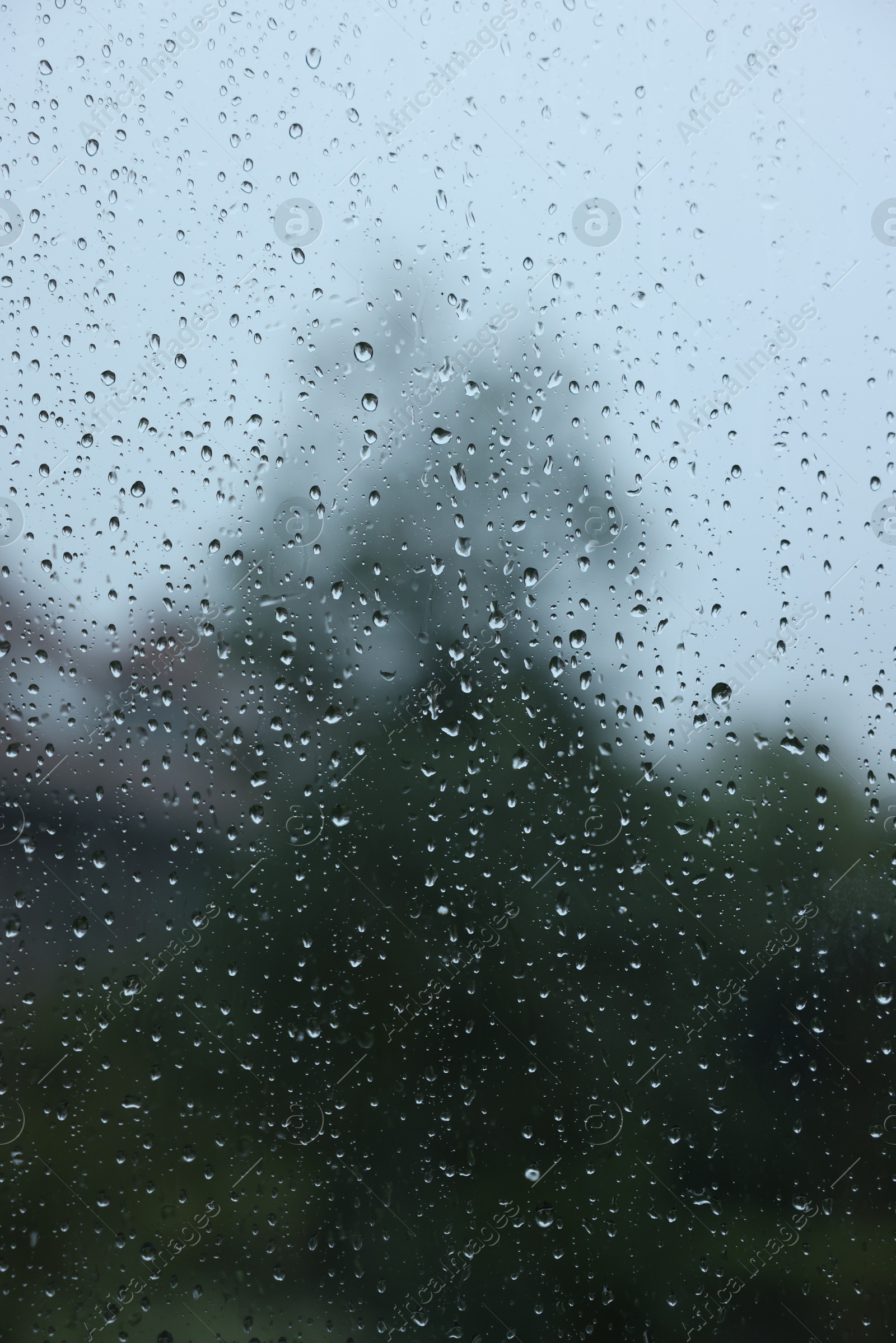 Photo of View on buildings through window with water droplets on rainy day, closeup