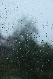 Photo of View on buildings through window with water droplets on rainy day, closeup