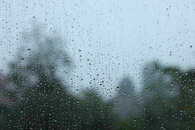 Photo of View on buildings through window with water droplets on rainy day, closeup