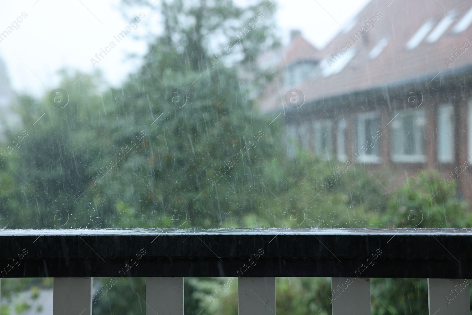 Photo of View on buildings and trees from balcony on rainy day