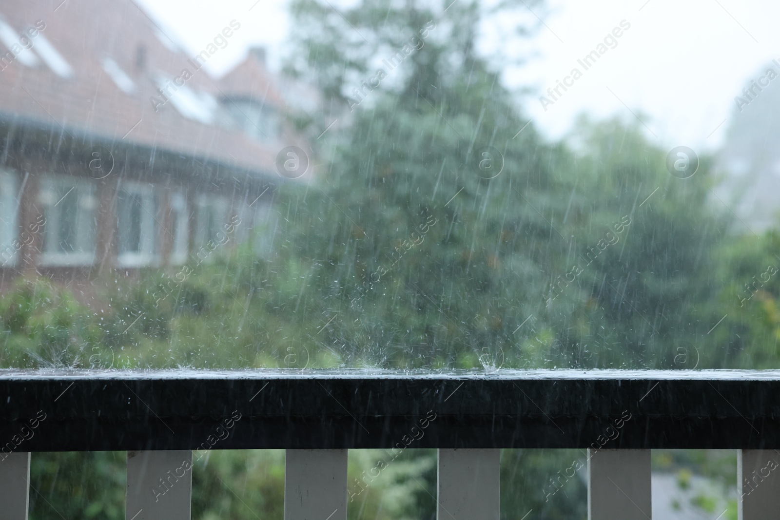 Photo of View on buildings and trees from balcony on rainy day