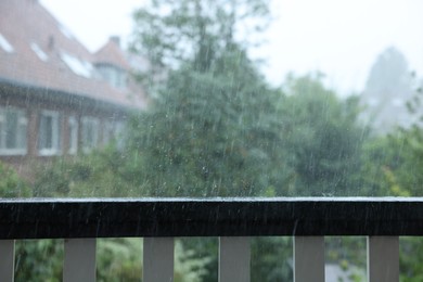 Photo of View on buildings and trees from balcony on rainy day