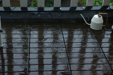 Watering can on wet balcony during rain