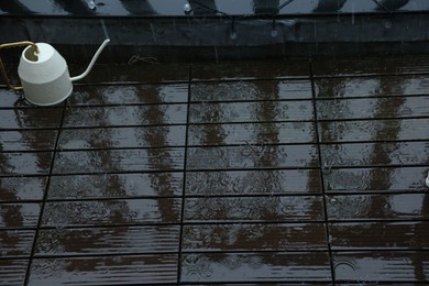 Photo of Watering can on wet balcony during rain