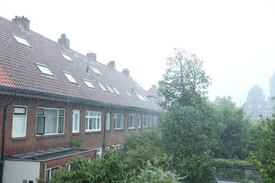 Photo of View of buildings and trees under pouring rain