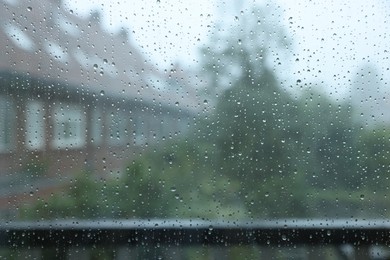 View on buildings through window with water droplets on rainy day, closeup