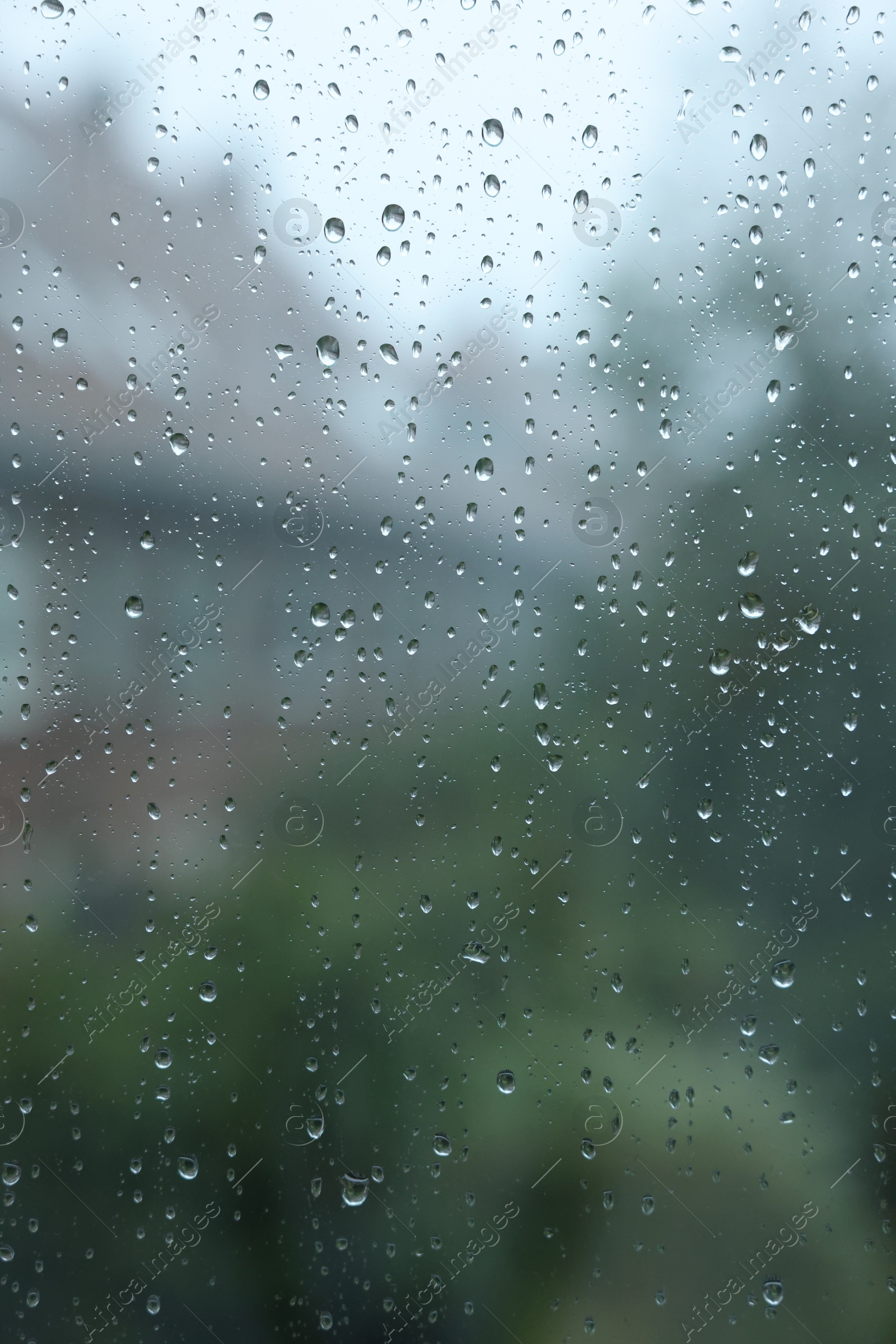 Photo of View on buildings through window with water droplets on rainy day, closeup