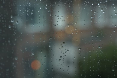 Photo of View on buildings through window with water droplets on rainy day, closeup