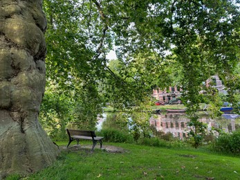 Photo of Beautiful view of wooden bench near canal in park