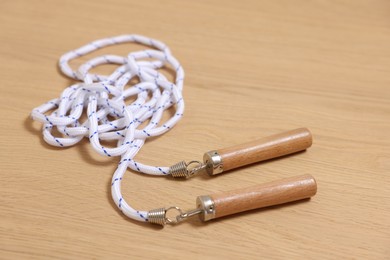 Photo of Skipping rope on wooden table, closeup. Sports equipment