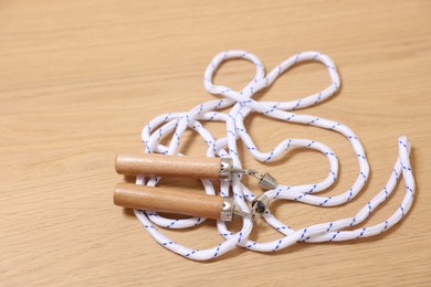 Photo of Skipping rope on wooden table, closeup. Sports equipment