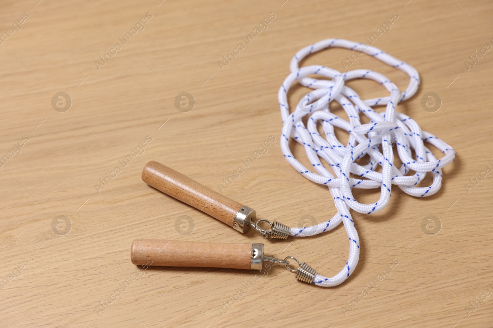 Photo of Skipping rope on wooden table, closeup. Sports equipment