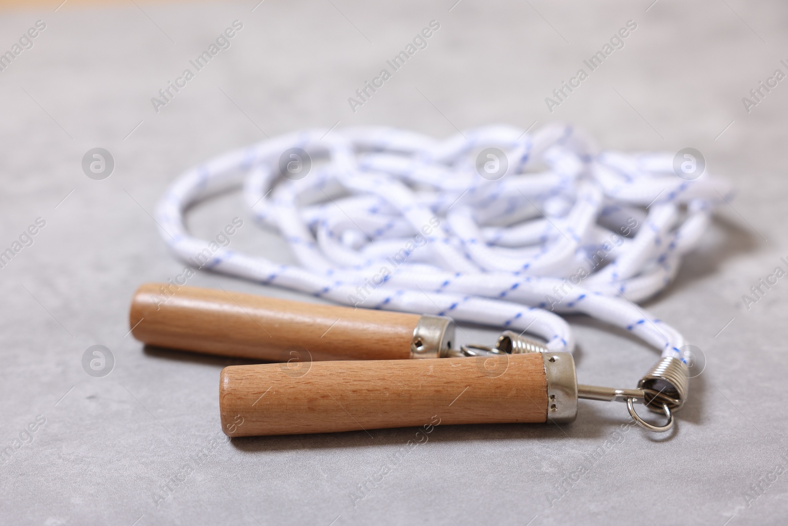 Photo of Skipping rope on grey table, closeup. Sports equipment