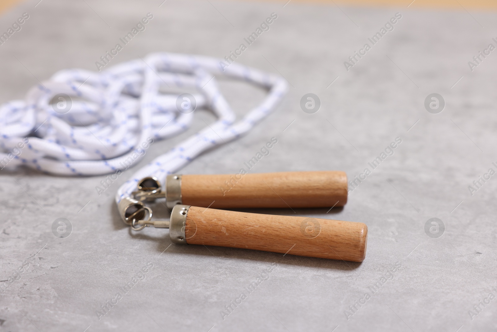 Photo of Skipping rope on grey table, closeup. Sports equipment