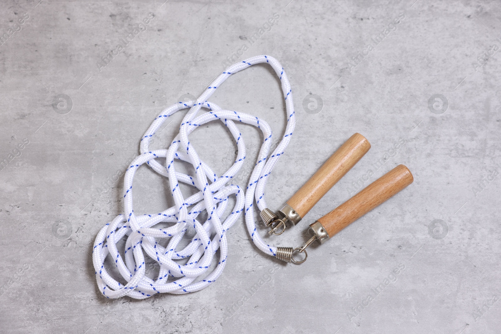 Photo of Skipping rope on grey table, top view. Sports equipment