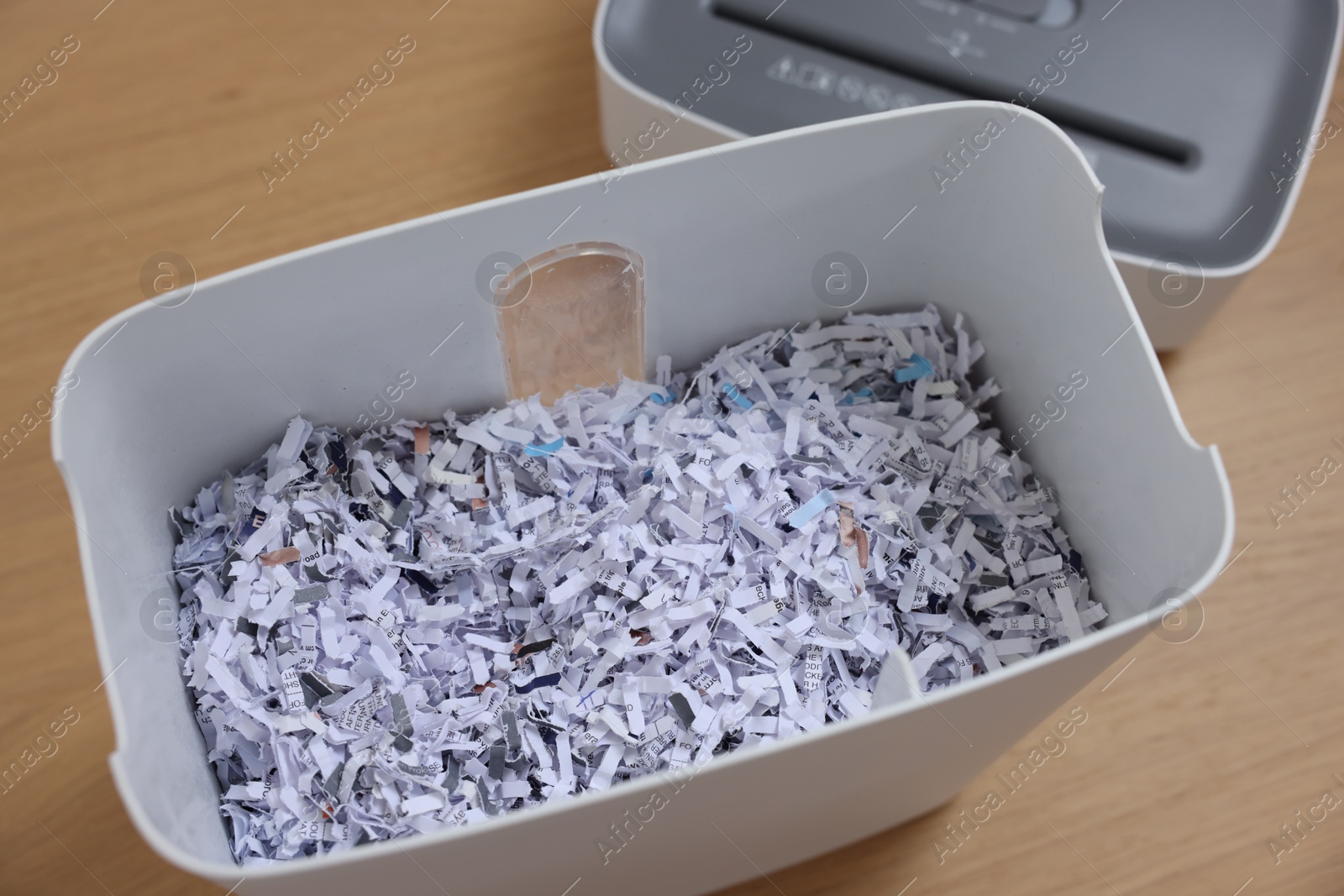 Photo of Shredder and basket with paper strips on wooden table, above view