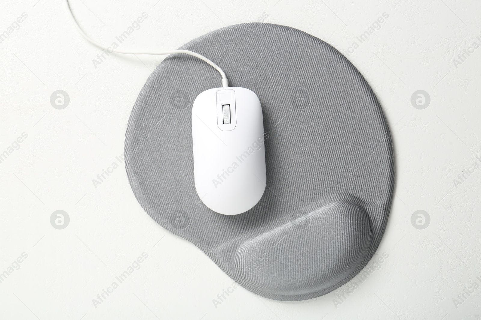 Photo of Computer mouse and mousepad with armrest on white table, top view