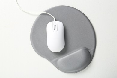 Photo of Computer mouse and mousepad with armrest on white table, top view