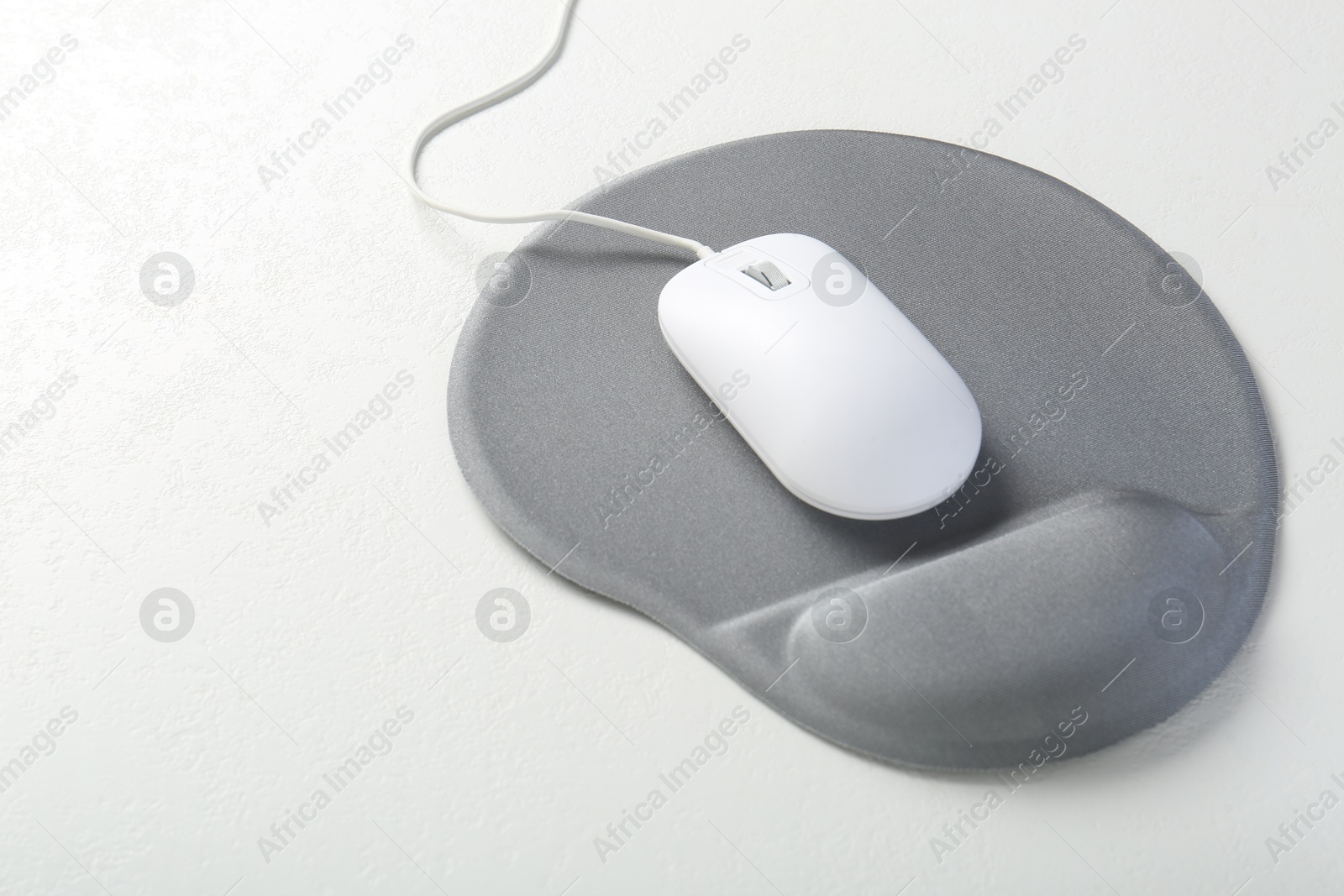 Photo of Computer mouse and mousepad with armrest on white table, space for text