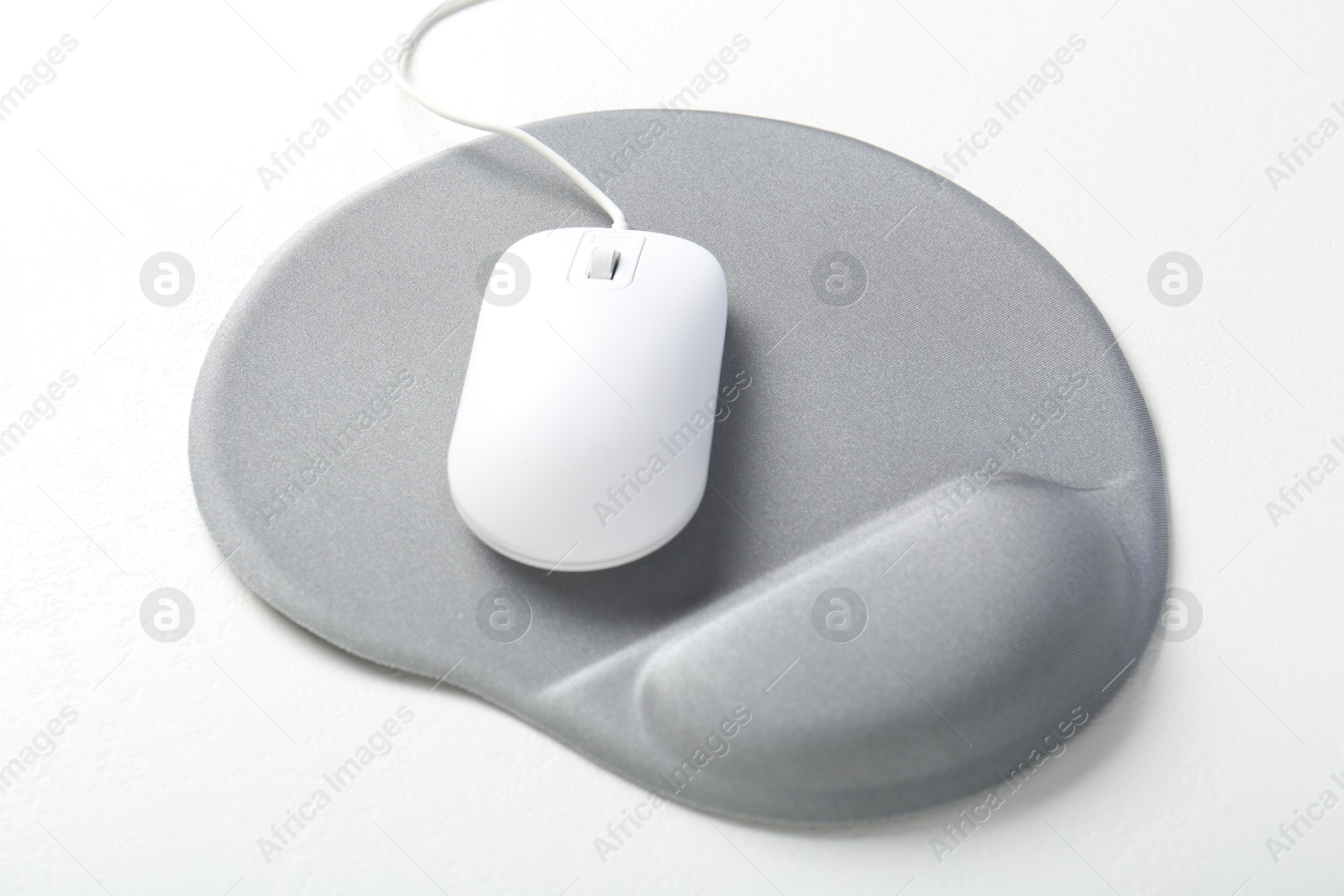 Photo of Computer mouse and mousepad with armrest on white table