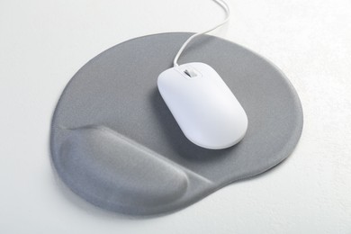 Photo of Computer mouse and mousepad with armrest on white table