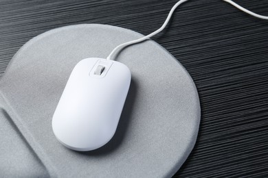 Photo of Computer mouse and mousepad on black wooden table