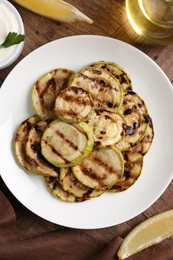 Photo of Tasty grilled courgette slices served on wooden table, flat lay