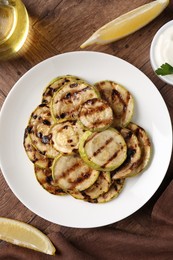 Tasty grilled courgette slices served on wooden table, flat lay