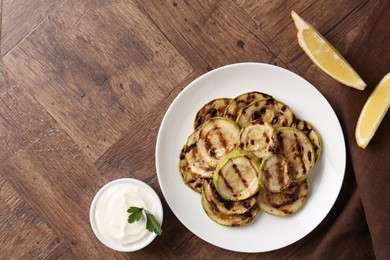 Photo of Tasty grilled courgette slices served on wooden table, flat lay. Space for text