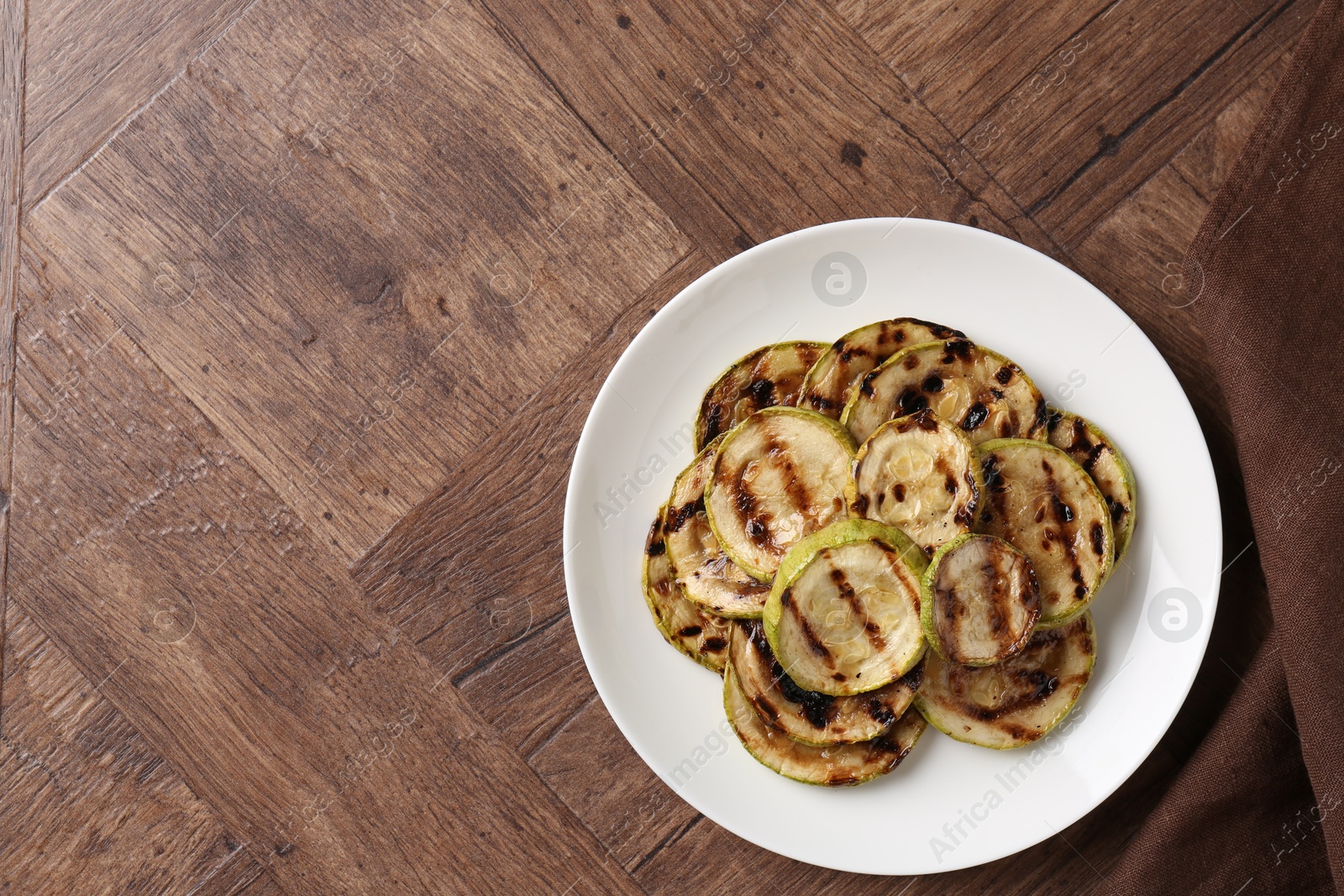 Photo of Tasty grilled courgette slices on wooden table, top view. Space for text