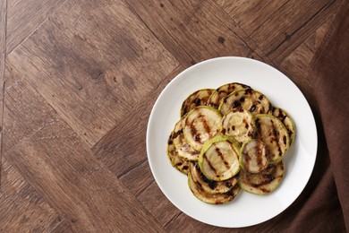 Photo of Tasty grilled courgette slices on wooden table, top view. Space for text