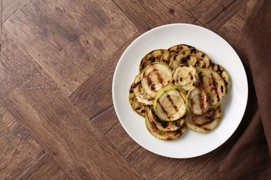 Tasty grilled courgette slices on wooden table, top view. Space for text