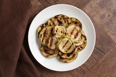 Tasty grilled courgette slices on wooden table, top view