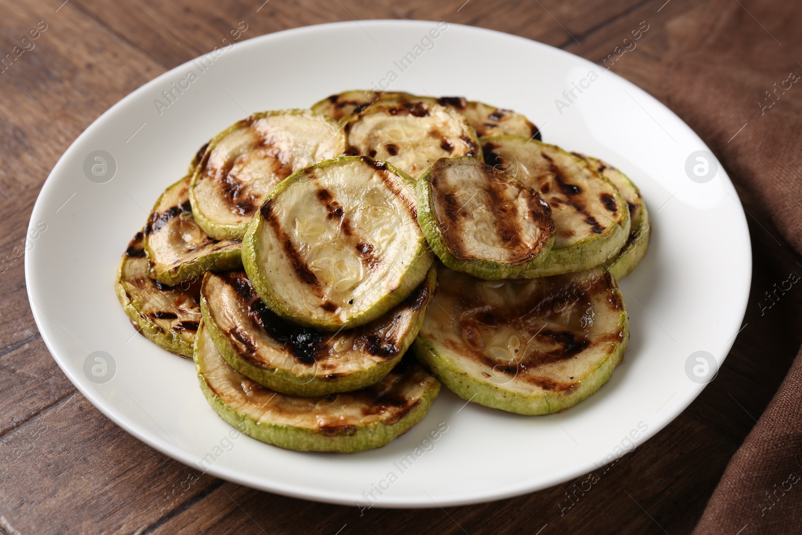 Photo of Tasty grilled courgette slices on wooden table