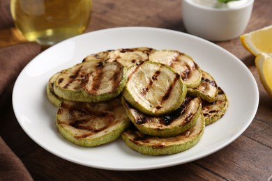 Tasty grilled courgette slices on wooden table