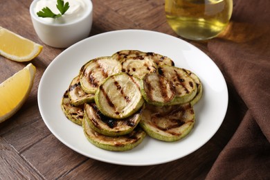 Photo of Tasty grilled courgette slices served on wooden table