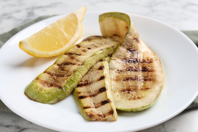 Tasty grilled courgette slices with lemon on white table