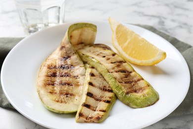 Photo of Tasty grilled courgette slices with lemon on white table