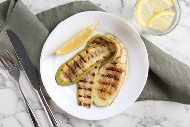 Tasty grilled courgette slices served on white marble table, flat lay