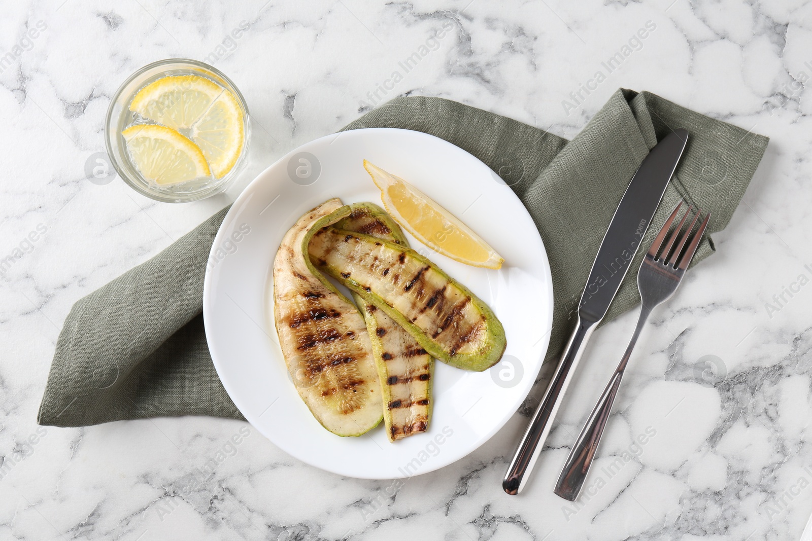 Photo of Tasty grilled courgette slices served on white marble table, flat lay