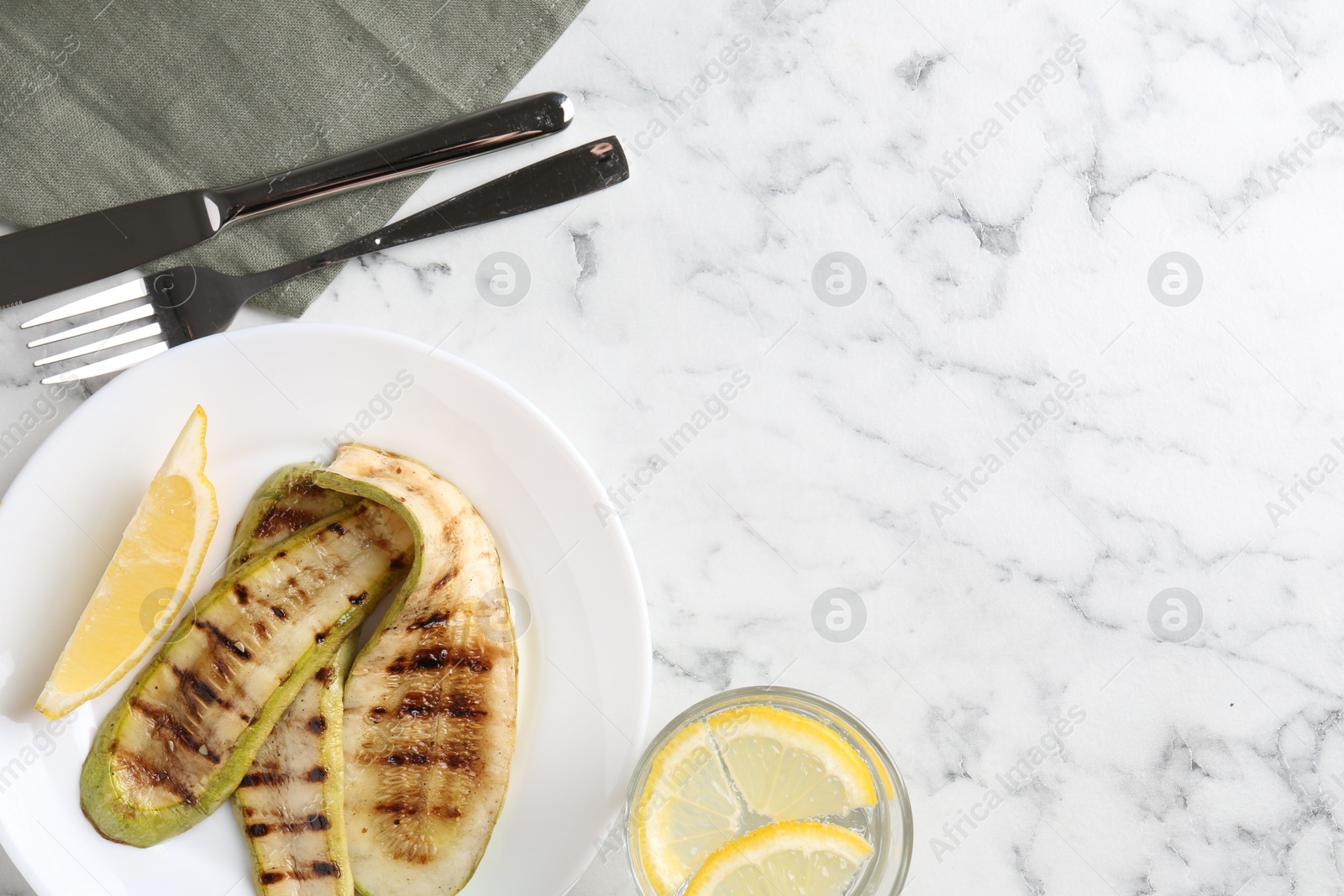 Photo of Tasty grilled courgette slices served on white marble table, flat lay. Space for text