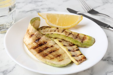 Photo of Tasty grilled courgette slices served on white marble table