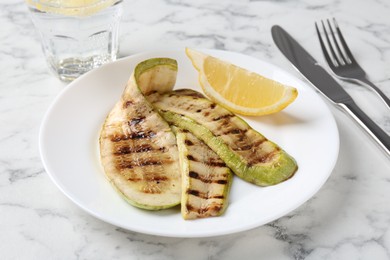 Tasty grilled courgette slices served on white marble table