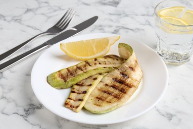 Photo of Tasty grilled courgette slices served on white marble table