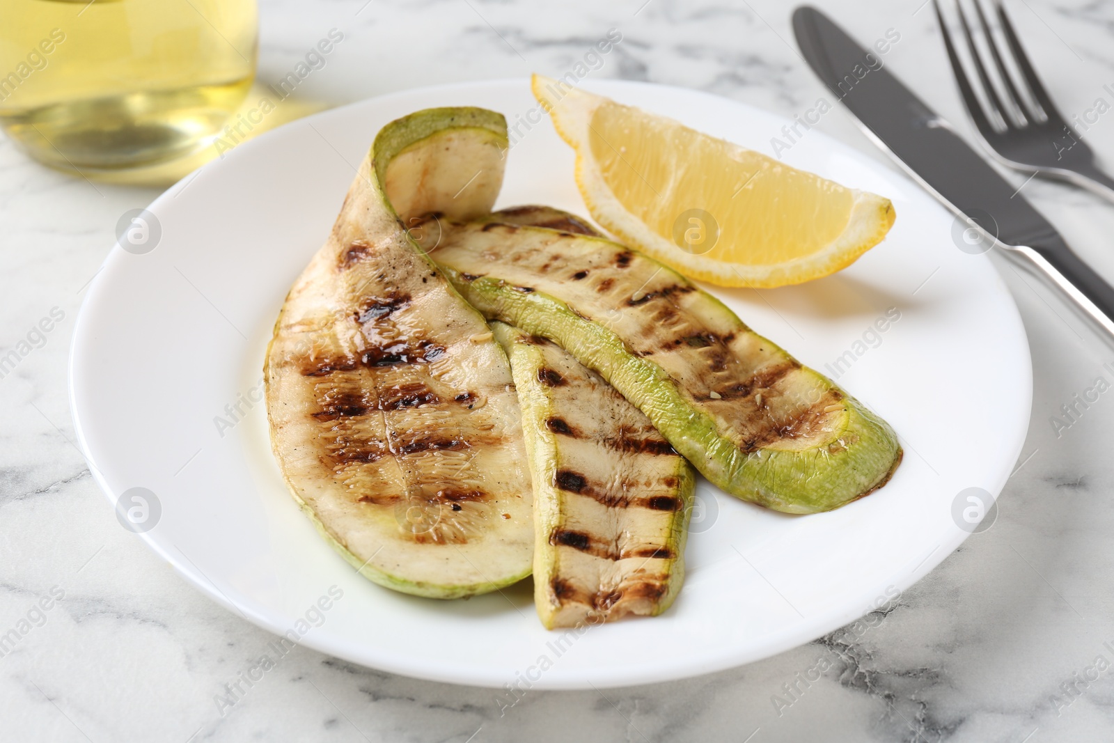 Photo of Tasty grilled courgette slices served on white marble table